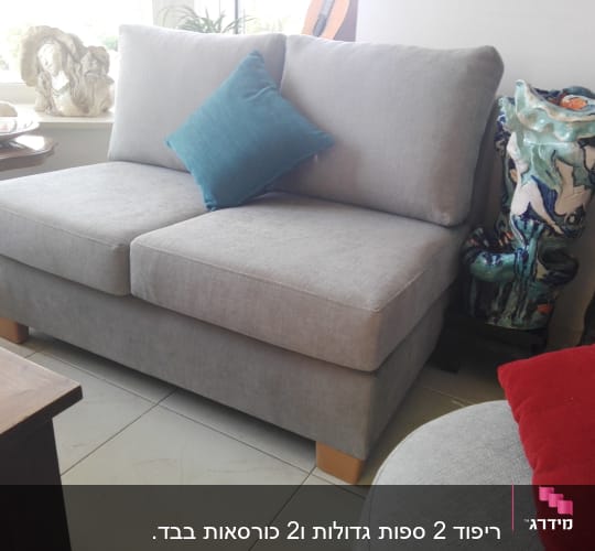 ספה אפורה עם כרית כחולה על רגלי עץ